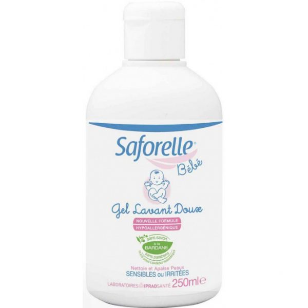 L'image montre une bouteille en plastique blanc de Saforelle Bébé Gel Lavant Doux, un gel nettoyant doux pour la peau sensible ou irritée de bébé. La bouteille a un bouchon rose et comporte une étiquette bleue et rose avec une illustration de bébé souriant. La taille du flacon est de 250 ml.