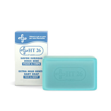 Une boîte et une barre de savon pour bébé extra doux HT26 pour le visage et le corps sont présentées. L'emballage est majoritairement blanc et bleu, avec des textes en français et en anglais. Le pain de savon est rectangulaire et bleu clair, arborant le logo HT26.