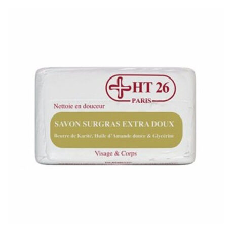 Un pain de savon blanc rectangulaire avec texte en français, arborant le logo de la marque HT 26 Paris. L'étiquette indique « Nettoue en douceur », « SAVON SURGRAS EXTRA DOUX » et mentionne des ingrédients comme le beurre de karité, l'huile d'amande douce et la glycérine, adaptés au visage et au corps.