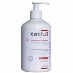 Un flacon blanc de Xerolys 5 avec un distributeur à pompe. L'étiquette indique qu'il s'agit d'un produit de soin émollient longue durée pour les peaux sèches. La bouteille comporte du texte rouge et noir, y compris des détails sur le produit et des logos, sur un fond clair.