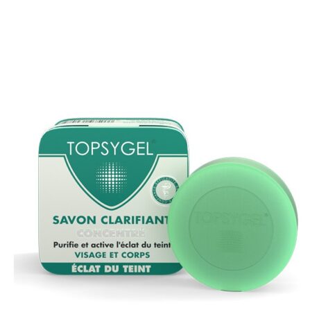Image d'un paquet de savon Topsygel "Savon Clarifiant" et d'un pain de savon. L'emballage est rectangulaire avec un motif vert et blanc, comprenant le logo Topsygel et le texte en français. Le pain de savon rond est vert, estampé de la marque Topsygel et placé devant l'emballage.