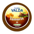 Un contenant rond de Pastilles Valda au goût de tamarin. L'étiquette montre des images de fruits de tamarin et de morceaux de bonbons au tamarin. Il indique « Sans sucre » et contient 60 pastilles. Le récipient a un bord marron.