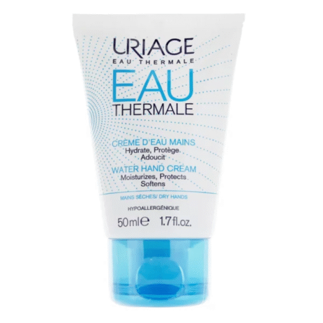 Un tube blanc de crème pour les mains Eau Thermale d'Uriage debout. La face avant, en français et en anglais, met en avant ses propriétés hydratantes, protectrices et adoucissantes. Le tube a un bouchon bleu et contient 50 ml (1,7 fl. oz.) de produit pour les mains sèches.