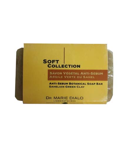 Un pain de savon dans un emballage en carton étiqueté « Soft Collection ». L'étiquette, en jaune, indique « Savon Végétal Anti-Sébum Argile Verte Du Sahel / Anti-Sebum Botanical Soap Bar Sahellan Green Clay ». Le packaging mentionne également « Dr Marie Dialo Laboratoires.
