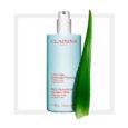 Une bouteille bleu clair de lait hydratant lissant pour le corps Clarins à l'aloe vera est présentée, avec un distributeur à pompe blanc sur le dessus. Le texte de l'étiquette est en français et en anglais. Une feuille d’aloe vera se dresse à côté de la bouteille. Le fond est blanc, encadré d'un carré gris clair.