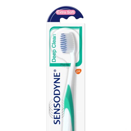 Image d'une brosse à dents Sensodyne Deep Clean dans son emballage d'origine. La brosse à dents est blanche avec des accents verts et bleus et étiquetée « Extra Soft ». L'emballage est principalement blanc avec des éléments turquoise et verts et le logo Sensodyne verticalement sur le côté gauche.