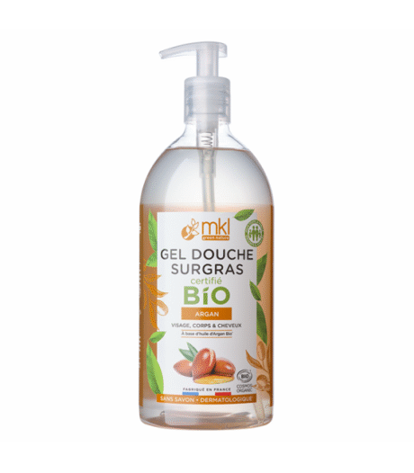 Un flacon transparent de gel douche à l'huile d'argan biologique MKL Green Nature avec un distributeur à pompe. L'étiquette présente des feuilles vertes et des noix d'argan et indique que le produit convient au visage, au corps et aux cheveux. Le texte est principalement en français.