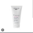Un tube blanc de 150 ml de crème nutritive pour les mains BYPHASSE est présenté. Le produit est conçu pour réparer et protéger la peau sèche, contient de la glycérine, du beurre de karité et de la provitamine B5. Le tube a un design épuré avec du texte noir et rouge et un capuchon argenté.