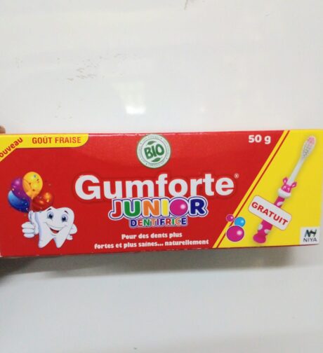 Une boîte de dentifrice rouge Gumforte Junior Dentifrice contenant 50 g de dentifrice aromatisé à la fraise. La boîte présente un personnage de dent souriant avec des ballons, un logo vert « BIO » et un texte soulignant les bienfaits du produit pour des dents fortes et saines. Une étiquette « Gratuit » est également affichée.