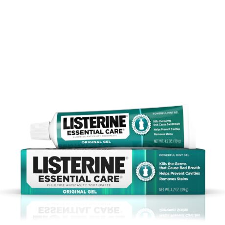 Un tube de dentifrice Gel Original Listerine Essential Care est placé sur le dessus de sa boîte assortie. L'emballage est vert et blanc, soulignant ses principaux avantages : tuer les germes responsables de la mauvaise haleine, aider à prévenir les caries et éliminer les taches.