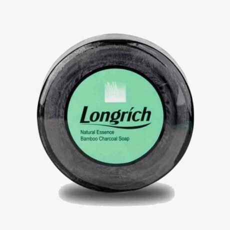 Une barre ronde de savon au charbon de bambou Longrich avec une étiquette verte sur le dessus tournée vers l'avant. L’étiquette du produit indique « Savon au charbon de bambou Longrich Natural Essence ». Le savon est noir et le fond est blanc uni.