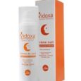 Un flacon blanc de Vidoxa crème de nuit est placé à côté de sa boîte d'emballage orange et blanche. Le produit prétend être sans paraben et adapté à une utilisation nocturne. La boîte présente une marque et une description similaires à celles de la bouteille.