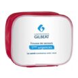 Une petite trousse de premiers secours rouge avec un devant blanc qui indique « Laboratoires Gilbert » en haut, suivi de « Trousse de secours 1ères urgences » au milieu et « La santé commence avec vous » en bas. Le logo des Laboratoires Gilbert est également affiché.