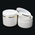Un pot cosmétique cylindrique blanc avec une bande dorée autour du couvercle, présenté sous deux perspectives : l'une fermée et l'autre sans le couvercle, révélant le récipient vide. Les deux sont placés sur un fond noir.