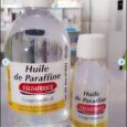 Deux bouteilles en plastique d'Huile de Paraffine avec bouchons blancs et étiquettes jaunes sont placées sur un comptoir. La plus grande bouteille est à gauche, tandis que la plus petite bouteille est à droite. Les deux étiquettes indiquent « Valdafrique » et indiquent un usage médical.