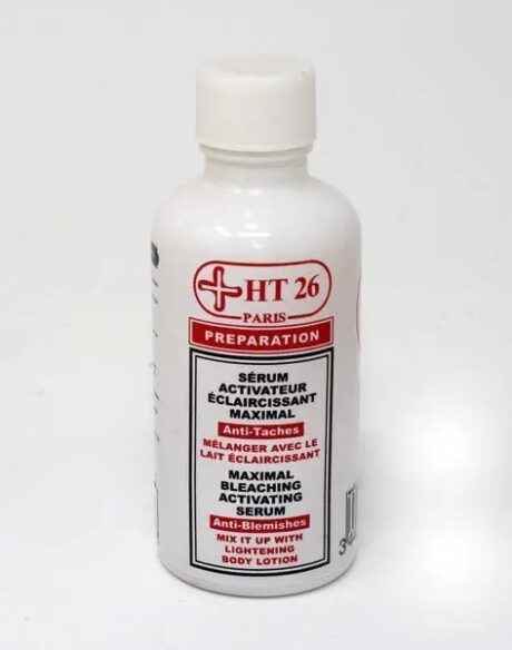 Un flacon blanc étiqueté « HT26 Sérum Activateur Eclaircissant Maximal 50 ml » contenant le Sérum Activateur de Blanchiment Maximal. Le texte indique qu'il est destiné aux anti-imperfections et doit être mélangé à une lotion corporelle éclaircissante. La bouteille a un bouchon blanc et un texte rouge et noir.