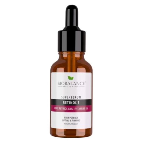 Un flacon compte-gouttes de BIOBALANCE Super Sérum Rétinol + Vitamine E est présenté. Le flacon en verre ambré a un bouchon compte-gouttes noir. L'étiquette indique que le produit contient 0,3 % de rétinol pur et 2 % de vitamine E pour un effet lifting et raffermissant très puissant. Le slogan de la marque se lit comme suit : « Face à la nature ».