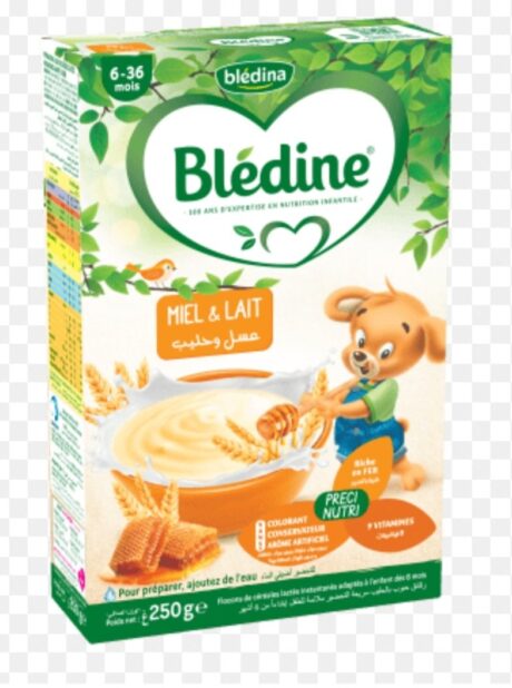 l'image montre une boîte de céréales pour bébé blédina de 6 à 36 mois. la saveur est du miel et du lait. l'emballage présente un ours remuant un bol de céréales avec des images de blé. la boîte ne contient aucun colorant ni conservateur artificiel et fournit des vitamines essentielles.