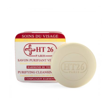 un savon nettoyant rond et beige estampillé « ht26 paris » est placé devant son emballage en boîte rouge et blanche. l'emballage comporte un texte sur ses propriétés purifiantes et harmonisantes pour le teint, enrichies en cold cream.
