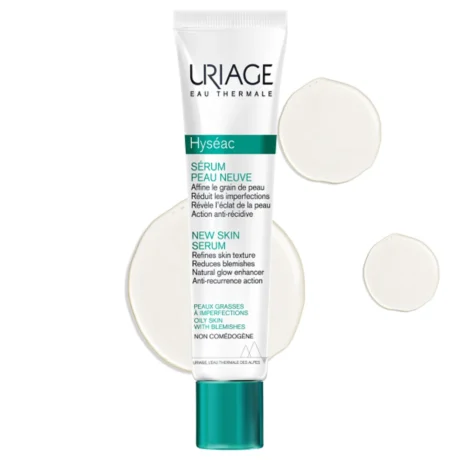 tube de sérum peau neuve hyseac d'uriage sur fond blanc. le tube est principalement blanc avec des éléments verts, comportant un texte sur ses bienfaits pour la texture de la peau et les imperfections. deux gouttes de liquide transparentes sont présentées à côté.