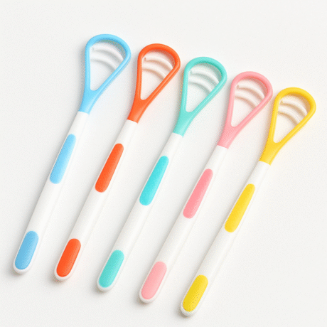 cinq gratte langues avec des poignées blanches et des poignées et têtes en caoutchouc colorées en bleu, orange, bleu sarcelle, rose et jaune sont disposés côte à côte sur un fond blanc.