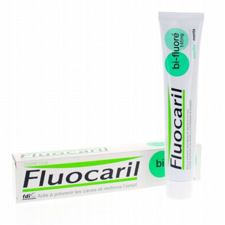 un tube de dentifrice fluocaril est posé à côté de sa boîte. les deux tubes arborent un texte vert et noir sur fond blanc. le dentifrice est étiqueté « bi fluoré 145 mg » avec un arôme « menthe ».
