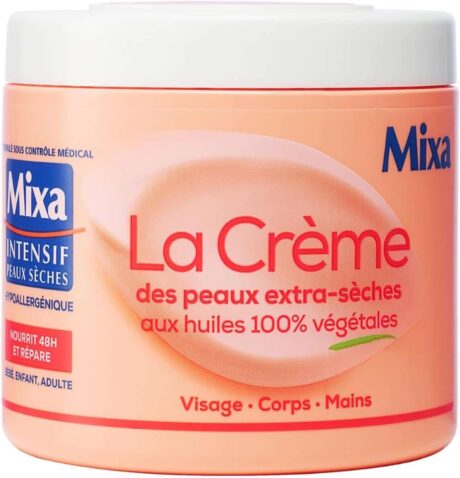 un pot de couleur pêche de mixa la crème pour peaux extra sèches, étiquetée comme hypoallergénique et contenant 100% d'huiles végétales. convient pour le visage, le corps et les mains. le texte de l'étiquette est en français.