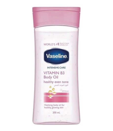une bouteille transparente de vaseline intensive care vitamin b3 body oil avec un bouchon rose, comportant un texte soulignant "healthy even tone" et contenant 200 ml. l'étiquette comporte également des graphiques et un peu de texte arabe.